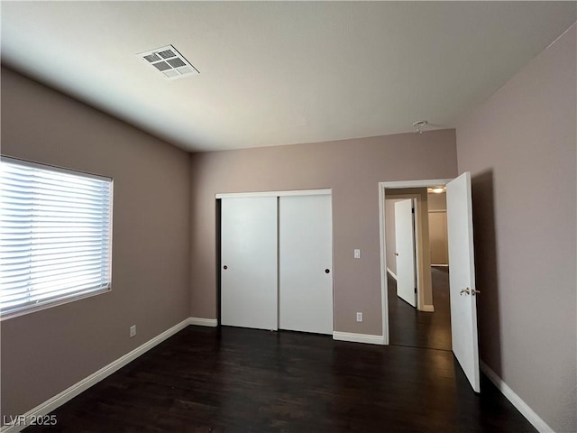 unfurnished bedroom featuring dark wood-type flooring and a closet