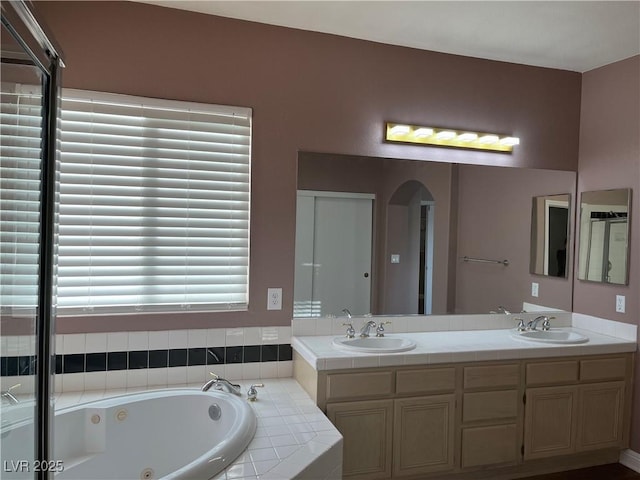bathroom with a tub with jets and double vanity