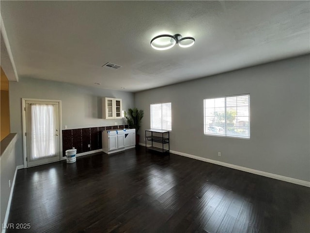 unfurnished living room featuring dark wood-style flooring and baseboards
