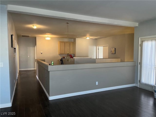 kitchen with dark wood-style flooring, light brown cabinetry, and a peninsula