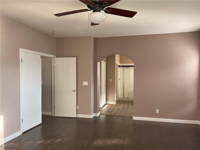 unfurnished room featuring arched walkways, ceiling fan, and wood finished floors
