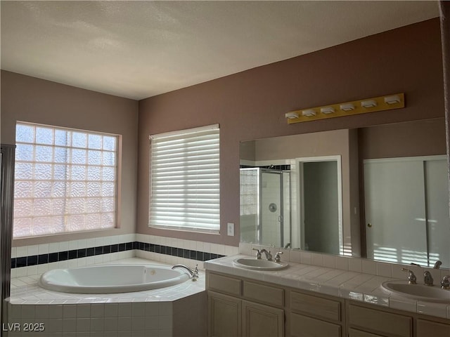 bathroom featuring a shower stall, a bath, and double vanity