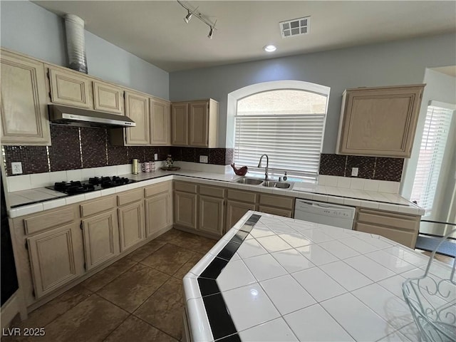 kitchen featuring under cabinet range hood, black gas stovetop, dishwasher, tile counters, and healthy amount of natural light