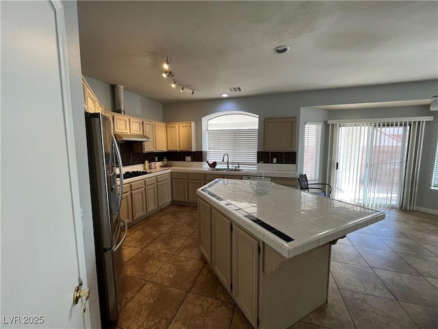 kitchen featuring freestanding refrigerator, tile counters, plenty of natural light, and tasteful backsplash