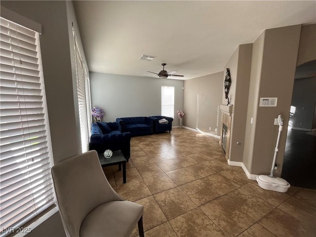 tiled living area featuring a ceiling fan and a tile fireplace