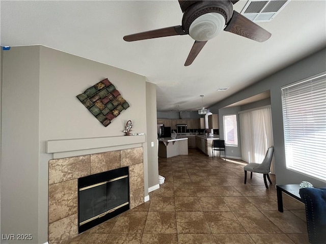 living area featuring a ceiling fan and a tile fireplace