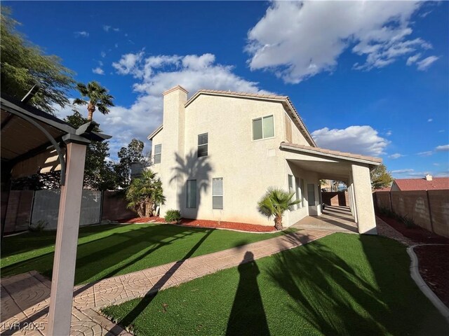 back of property with stucco siding, a fenced backyard, and a chimney