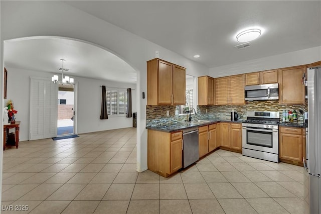 6430 Jackrabbit Run Ave, Las Vegas, NV 89122 - kitchen with appliances with stainless steel finishes, a chandelier, decorative backsplash, light tile patterned floors, and arched walkways