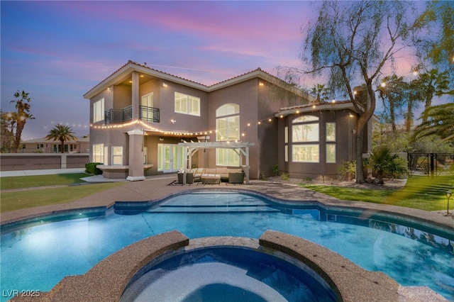 7520 Captains Harbor Dr, Las Vegas, NV 89117 - back of house at dusk with a balcony, an outdoor hangout area, stucco siding, a pool with connected hot tub, and a tiled roof