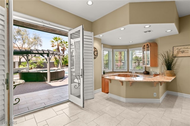 7520 Captains Harbor Dr, Las Vegas, NV 89117 - kitchen featuring light stone counters, a breakfast bar, recessed lighting, a peninsula, and glass insert cabinets