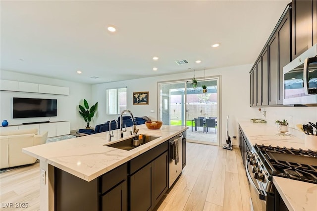 1289 Valencia Cliffs Ave, Henderson, NV 89012 - kitchen featuring appliances with stainless steel finishes, light wood-type flooring, light stone countertops, an island with sink, and recessed lighting