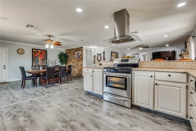 5403 Tamarus St, Las Vegas, NV 89119 - kitchen with stainless steel gas range, a ceiling fan, island range hood, ornamental molding, and white cabinetry