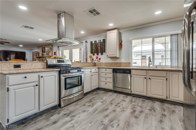 5403 Tamarus St, Las Vegas, NV 89119 - kitchen with appliances with stainless steel finishes, island exhaust hood, ornamental molding, a peninsula, and light wood-style flooring