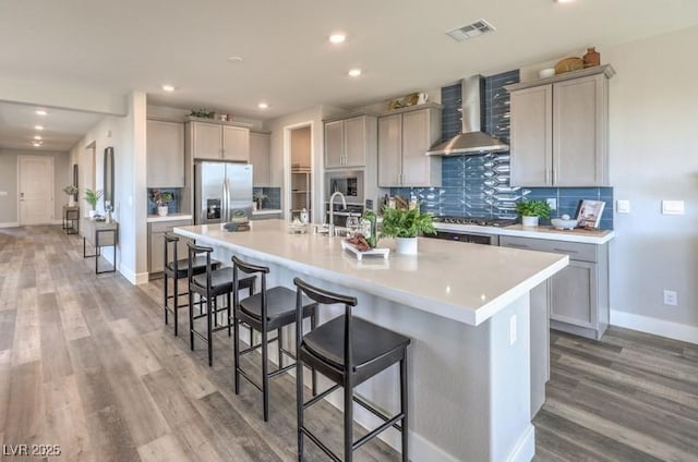 1408 Eva Creek Dr Unit 27, North Las Vegas, NV 89084 - kitchen featuring wall chimney range hood, appliances with stainless steel finishes, light wood-style flooring, a kitchen breakfast bar, and recessed lighting