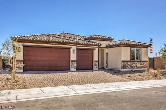 1408 Eva Creek Dr Unit 27, North Las Vegas, NV 89084 - mediterranean / spanish home featuring stone siding, driveway, stucco siding, a garage, and a tiled roof