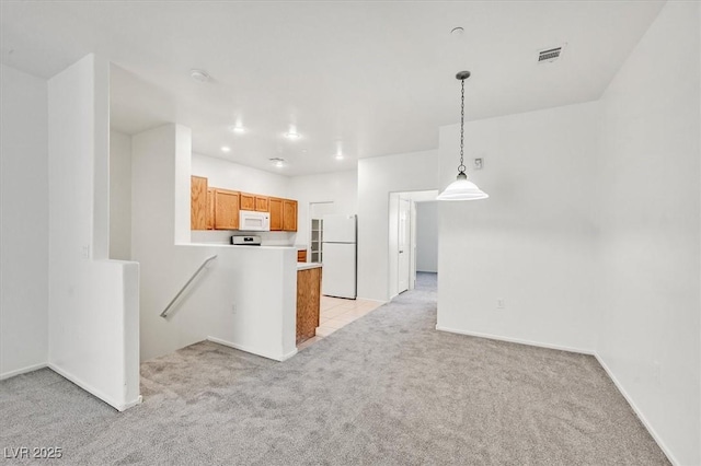 5960 Palmilla St Unit 7, North Las Vegas, NV 89031 - kitchen with white appliances, light carpet, a peninsula, light countertops, and hanging light fixtures