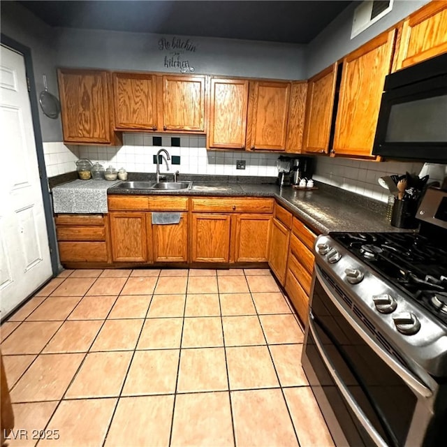 2709 Carroll St, North Las Vegas, NV 89030 - kitchen with range with two ovens, black microwave, brown cabinets, decorative backsplash, and light tile patterned flooring