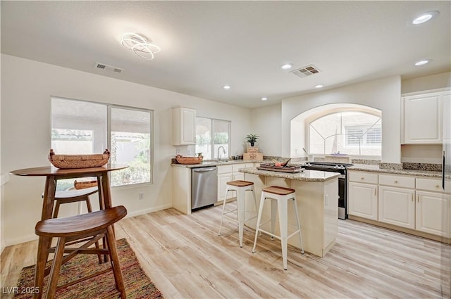 10921 Calcedonian St, Las Vegas, NV 89141 - kitchen featuring stainless steel appliances, arched walkways, a center island, white cabinetry, and light stone countertops