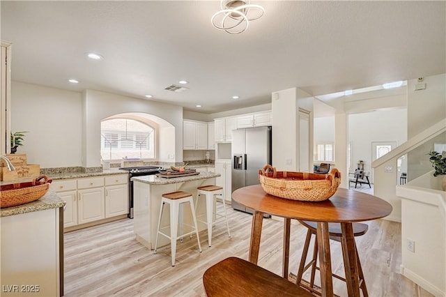 10921 Calcedonian St, Las Vegas, NV 89141 - kitchen with stainless steel appliances, light wood finished floors, light stone counters, a center island, and white cabinetry