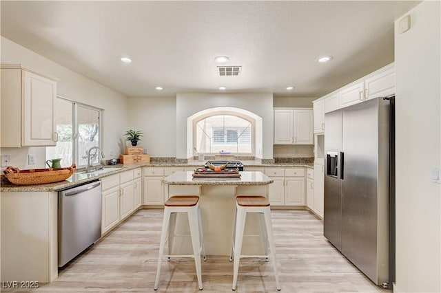 10921 Calcedonian St, Las Vegas, NV 89141 - kitchen with appliances with stainless steel finishes, a center island, light stone counters, light wood finished floors, and recessed lighting