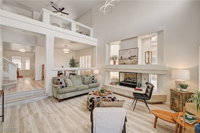 10921 Calcedonian St, Las Vegas, NV 89141 - living area with a towering ceiling, a fireplace, wood finished floors, a ceiling fan, and stairway