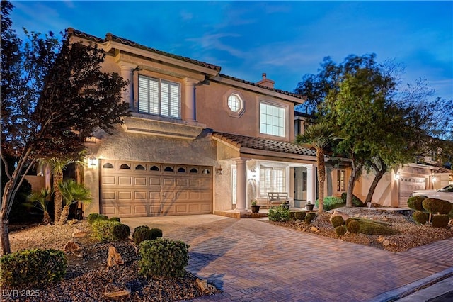 10921 Calcedonian St, Las Vegas, NV 89141 - mediterranean / spanish house with a chimney, decorative driveway, a garage, a tiled roof, and stucco siding