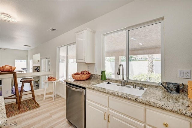 10921 Calcedonian St, Las Vegas, NV 89141 - kitchen featuring dishwasher, light wood-style floors, white cabinetry, and light stone counters