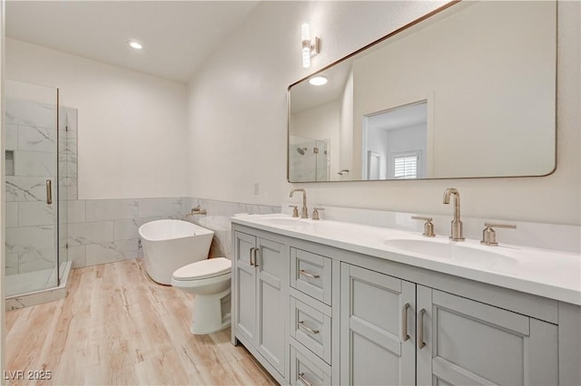 10921 Calcedonian St, Las Vegas, NV 89141 - bathroom with a marble finish shower, double vanity, a freestanding bath, tile walls, and wood finished floors