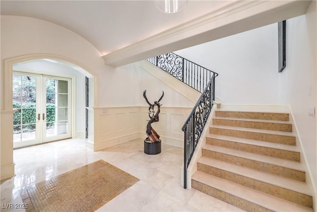 30 Augusta Canyon Way, Las Vegas, NV 89141 - stairway featuring arched walkways, french doors, a decorative wall, vaulted ceiling, and wainscoting
