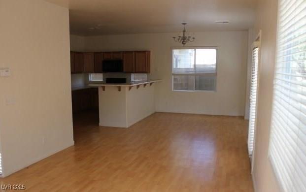 3711 Lodina Ct, Las Vegas, NV 89141 - kitchen with a breakfast bar, a chandelier, brown cabinets, light wood finished floors, and a peninsula