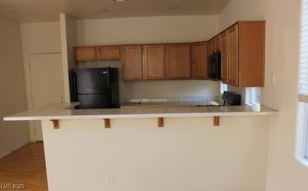 3711 Lodina Ct, Las Vegas, NV 89141 - kitchen featuring black appliances, brown cabinetry, and a kitchen bar