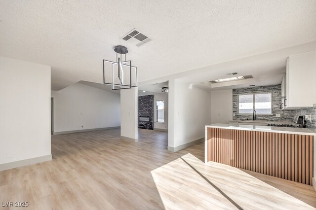 3425 Irv Marcus Dr, Las Vegas, NV 89108 - kitchen with a fireplace, white cabinetry, open floor plan, plenty of natural light, and a textured ceiling