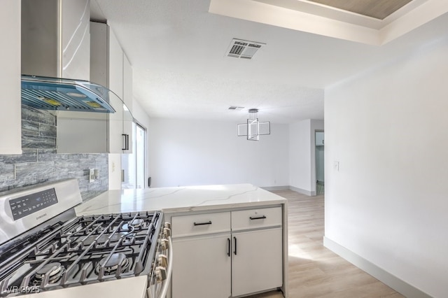 3425 Irv Marcus Dr, Las Vegas, NV 89108 - kitchen with stainless steel gas range oven, wall chimney range hood, light wood-style flooring, tasteful backsplash, and a peninsula