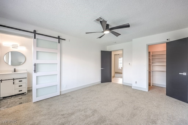 3425 Irv Marcus Dr, Las Vegas, NV 89108 - unfurnished bedroom featuring a barn door, light carpet, a spacious closet, a textured ceiling, and a closet