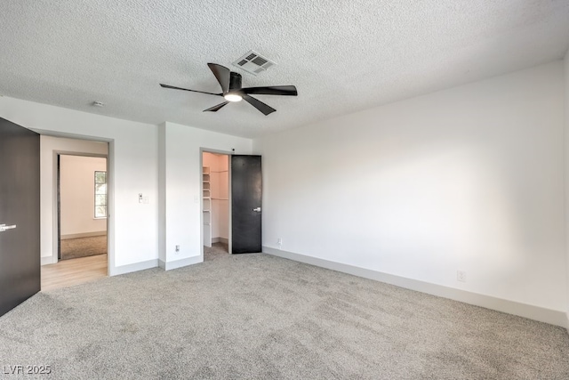 3425 Irv Marcus Dr, Las Vegas, NV 89108 - unfurnished bedroom with light colored carpet, a walk in closet, a textured ceiling, a closet, and a ceiling fan