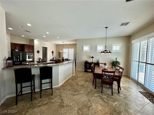 2257 Turner Falls St, Henderson, NV 89044 - kitchen with high end black fridge, stainless steel oven, recessed lighting, decorative light fixtures, and dark stone countertops