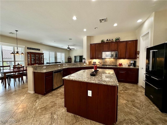 2257 Turner Falls St, Henderson, NV 89044 - kitchen featuring stainless steel appliances, a peninsula, decorative backsplash, light stone countertops, and a center island