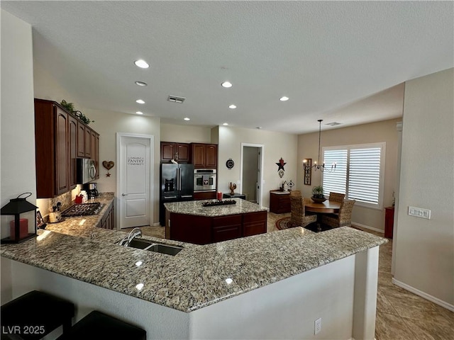 2257 Turner Falls St, Henderson, NV 89044 - kitchen featuring appliances with stainless steel finishes, light stone counters, a kitchen island, a peninsula, and recessed lighting