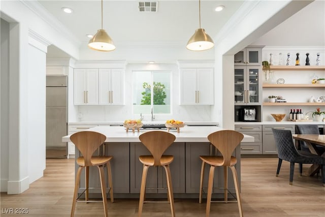 11830 Kingsbarns Ct, Las Vegas, NV 89141 - kitchen with paneled fridge, light countertops, crown molding, decorative light fixtures, and open shelves