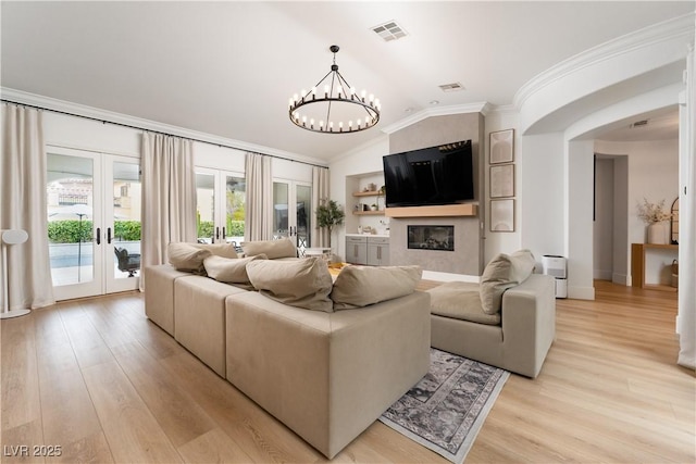 11830 Kingsbarns Ct, Las Vegas, NV 89141 - living room featuring french doors, ornamental molding, arched walkways, light wood-type flooring, and a chandelier
