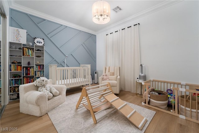 11830 Kingsbarns Ct, Las Vegas, NV 89141 - bedroom featuring a chandelier, wood finished floors, crown molding, a decorative wall, and a crib