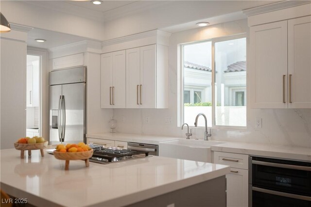 11830 Kingsbarns Ct, Las Vegas, NV 89141 - kitchen with appliances with stainless steel finishes, wine cooler, white cabinets, light countertops, and decorative backsplash