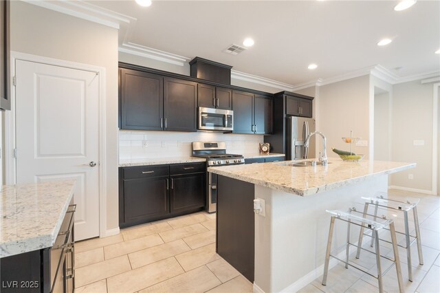 12478 Dolan Point St, Las Vegas, NV 89138 - kitchen with stainless steel appliances, backsplash, a breakfast bar area, a center island with sink, and crown molding