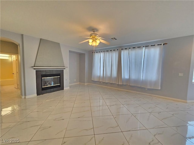 7428 Timber Run St, Las Vegas, NV 89149 - unfurnished living room with ceiling fan, arched walkways, light marble finish flooring, and a tile fireplace