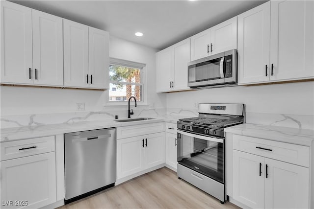 4186 Toronto Cir, Las Vegas, NV 89121 - kitchen with appliances with stainless steel finishes, recessed lighting, white cabinetry, light stone countertops, and light wood finished floors