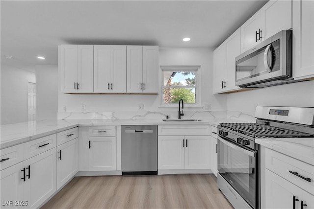 4186 Toronto Cir, Las Vegas, NV 89121 - kitchen with appliances with stainless steel finishes, recessed lighting, white cabinets, light stone counters, and light wood-type flooring