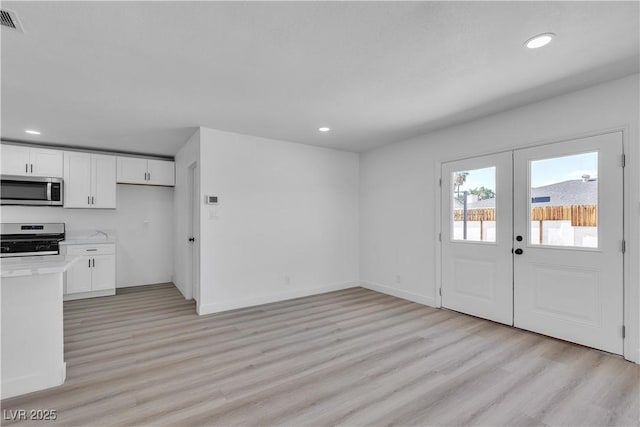 4186 Toronto Cir, Las Vegas, NV 89121 - kitchen with stainless steel microwave, electric range, light wood-style flooring, recessed lighting, and white cabinetry