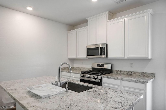 1110 Crystal Grotto Ave, North Las Vegas, NV 89081 - kitchen featuring stainless steel appliances, a center island with sink, white cabinets, light stone counters, and recessed lighting