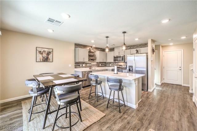 619 Harmony Rock Ave, North Las Vegas, NV 89081 - kitchen with stainless steel appliances, light countertops, a breakfast bar, tasteful backsplash, and a center island