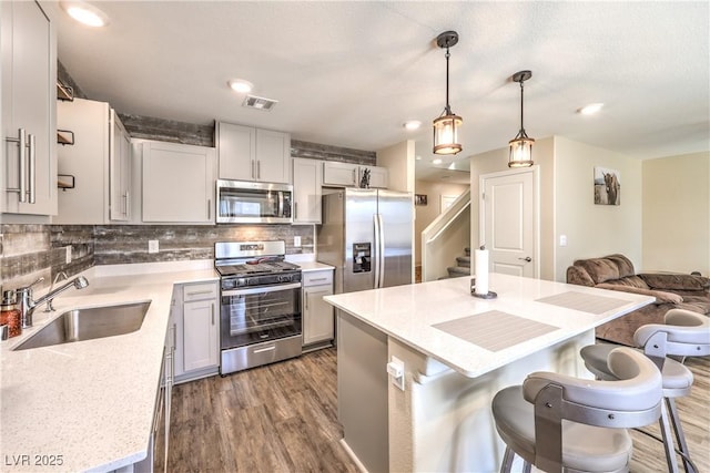 619 Harmony Rock Ave, North Las Vegas, NV 89081 - kitchen with appliances with stainless steel finishes, a kitchen bar, tasteful backsplash, dark wood-type flooring, and recessed lighting